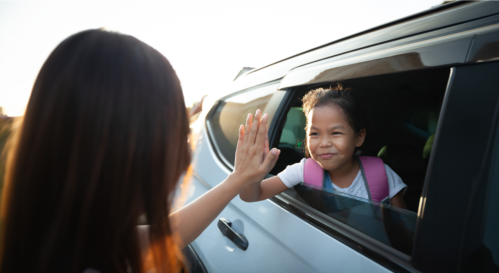 Mom and child high fiving in car